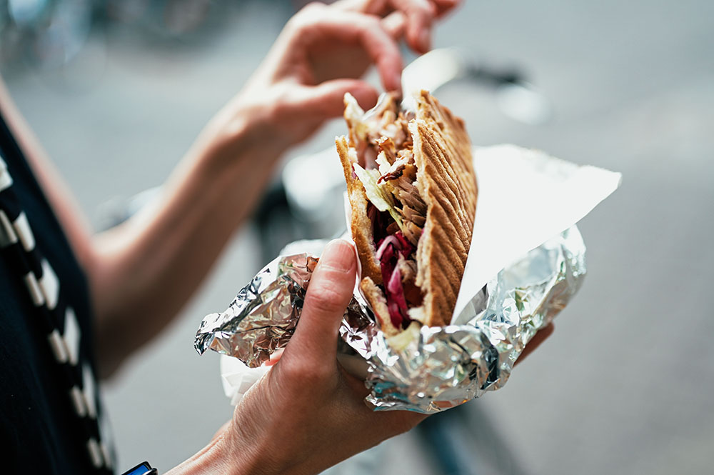 En kvinna äter döner kebab ute på gatan